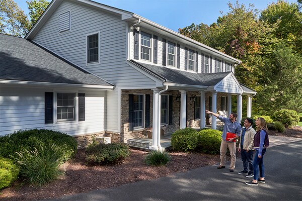 Insurance restoration roofing contractor outside home with homeowners  