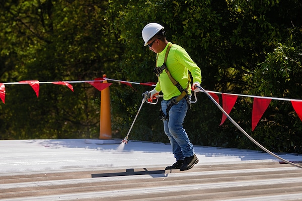 Roofing contractor spraying coating on flat roof