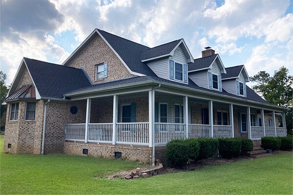Timberline HDZ shingles in the color Charcoal installed on a beige brick house.