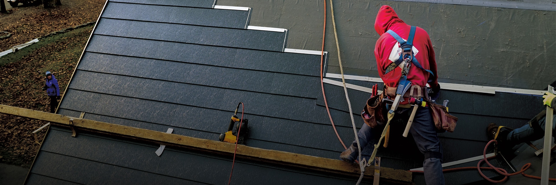 Certified GAF roofing contractor installing a metal roof shingle on a home