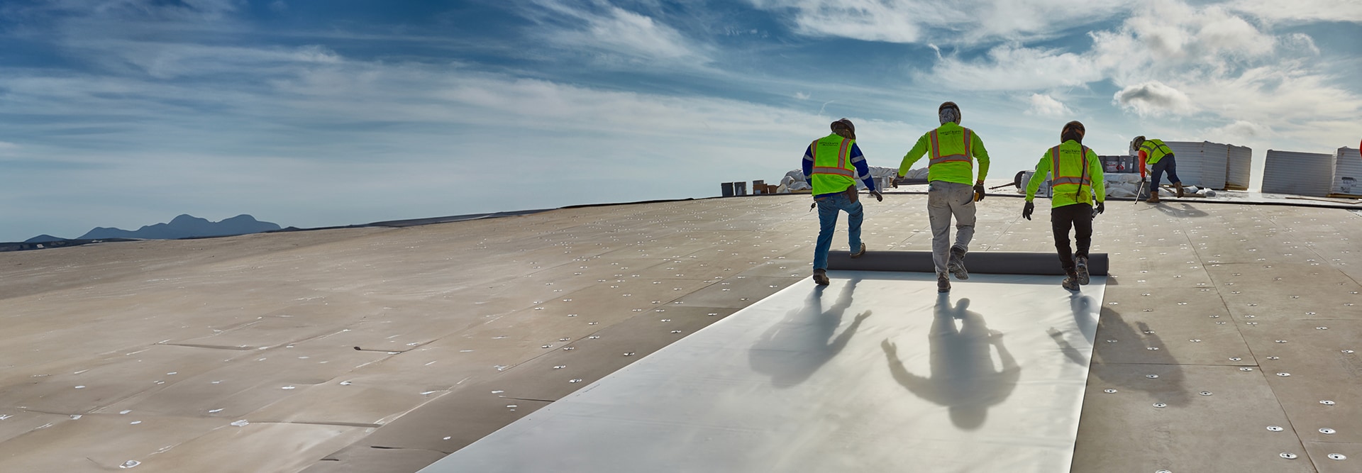 Commercial roofing contractors laying out PVC roofing materials by GAF
