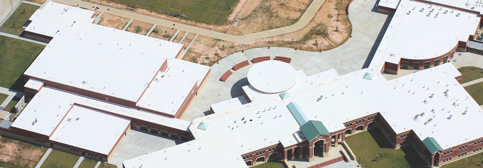 Aerial view of a sprawling school facility featuring a white commercial roofing system.