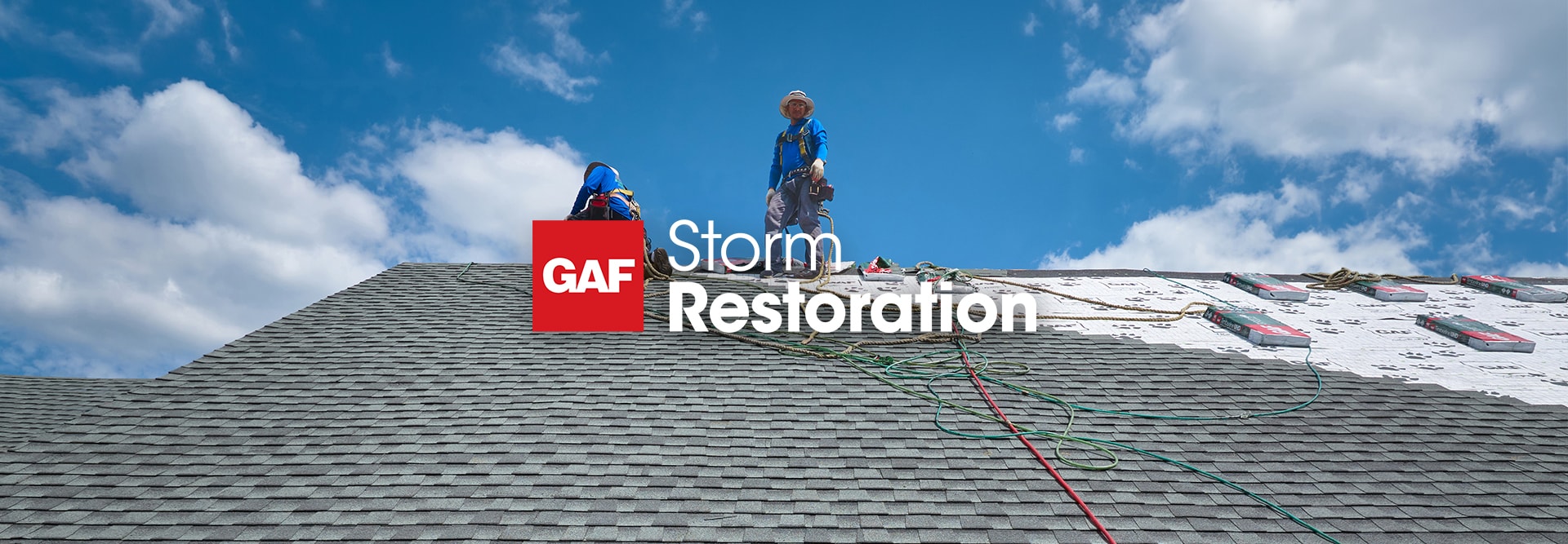 Aerial view of a home with a large blue tarp covering a damaged roof, featuring the GAF storm restoration logo at the top of the image.