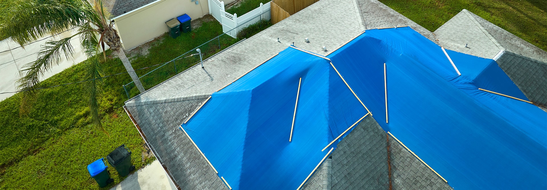 Blue tarps laid by GAF Certified contractors on top of a storm-damaged roof  to prevent the chances of additional water damage. 