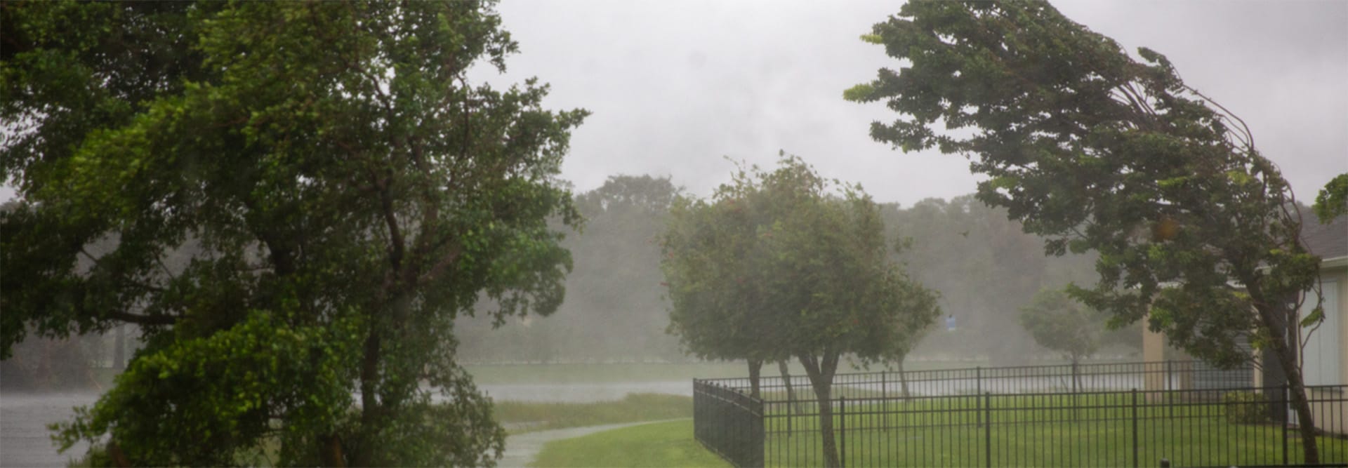 A residential neighborhood experiencing strong winds from a storm, where homes can benefit from the GAF WindProven Limited Wind Warranty that features no maximum wind speed limit.