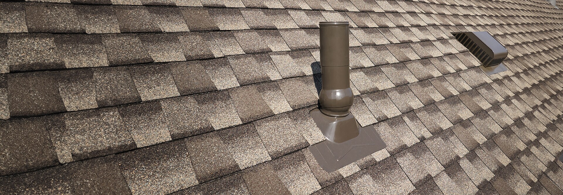 A close-up view of an asphalt shingle roof featuring GAF roof accessories that can help reduce water penetration. 