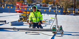 GAF certified contractors operating automated hot-air seam welders on an EverGuard TPO commercial roof.
