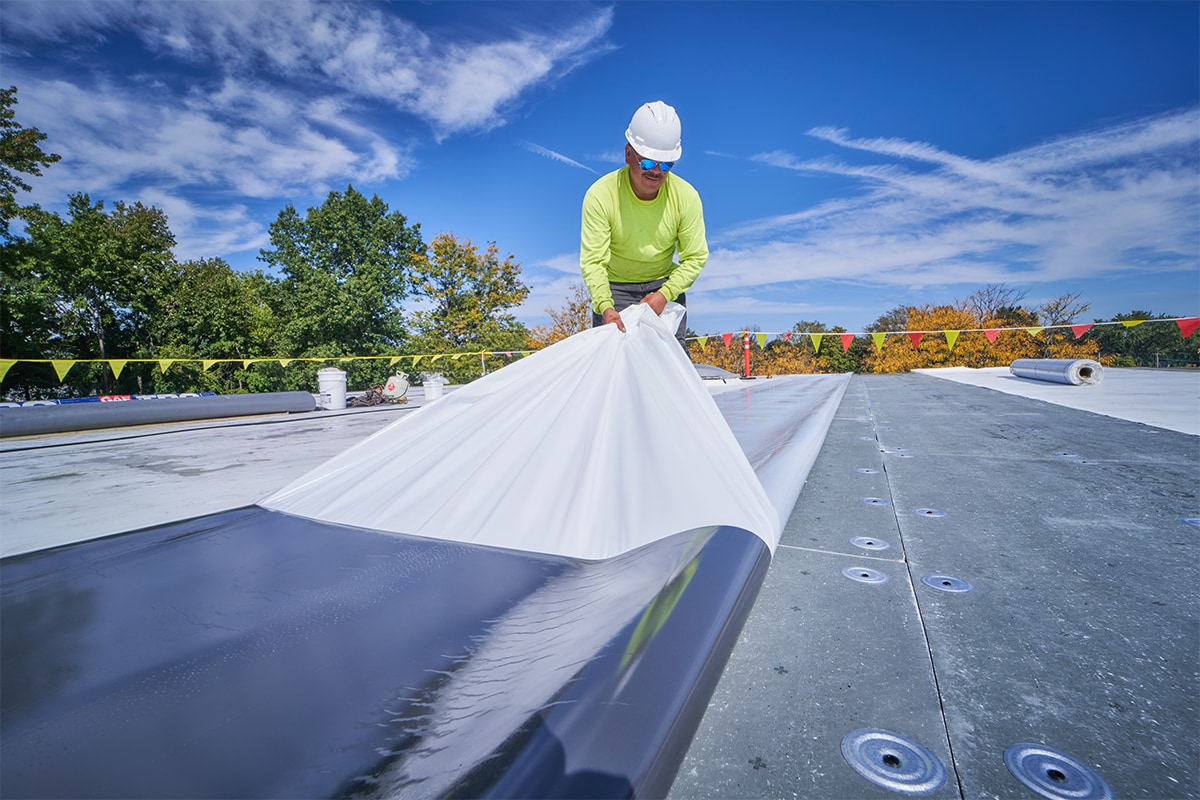 a roofing contractor installing a self adhesive roofing membrane