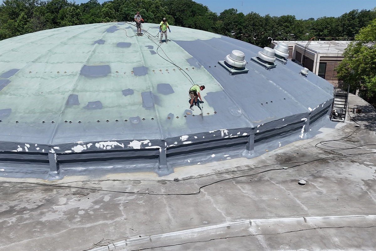 Commercial roofing contractors applying GAF High Solids Silicone coating layers on Normandy High School dome
