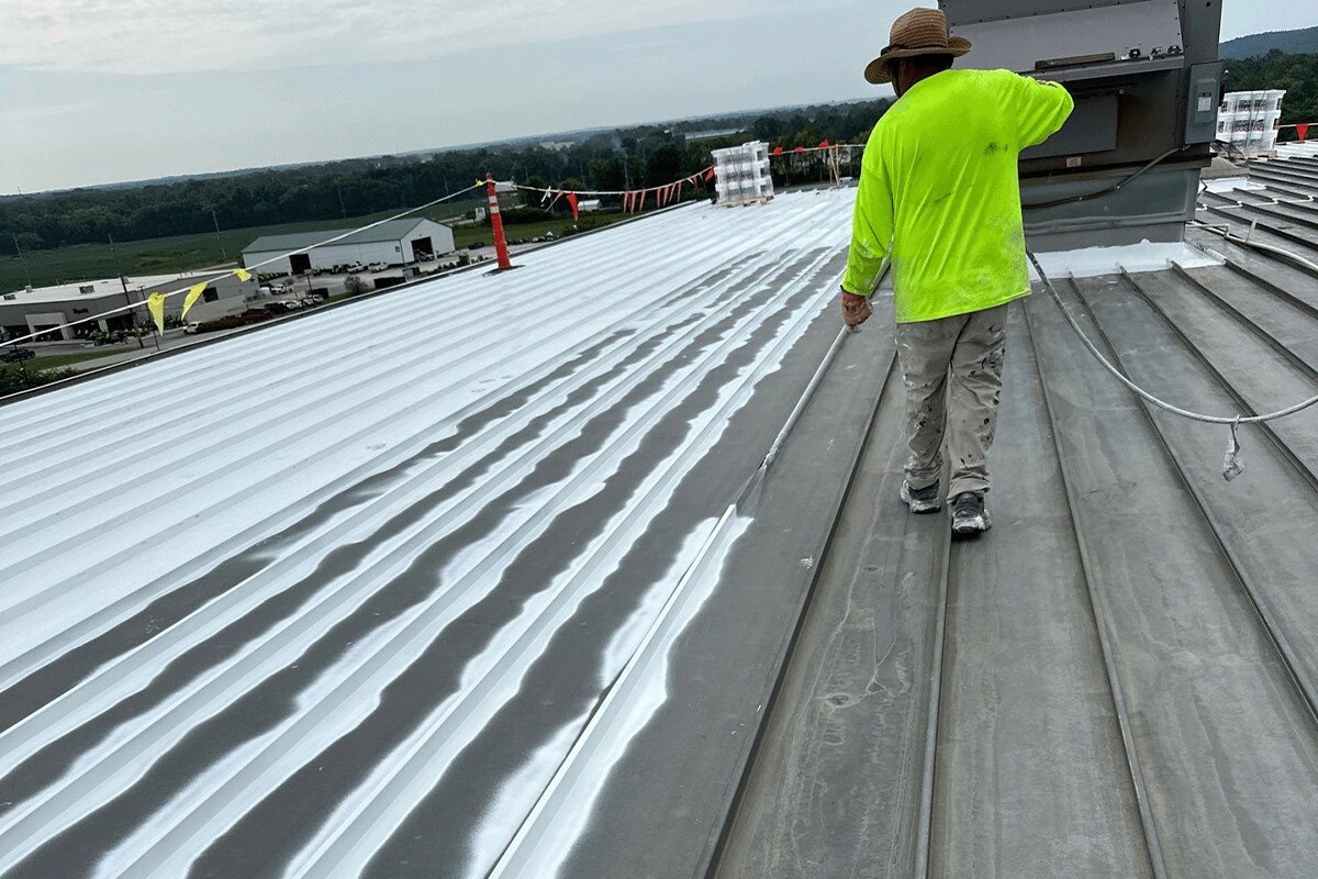 GAF certified coatings contractor on TOA USA metal roof coating the roof with silicone using a sprayer.