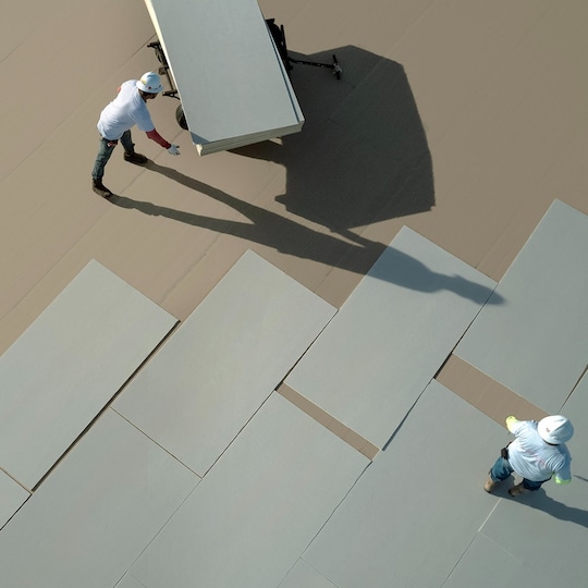 Commercial roofing contractors laying out EverGuard NH polyiso materials