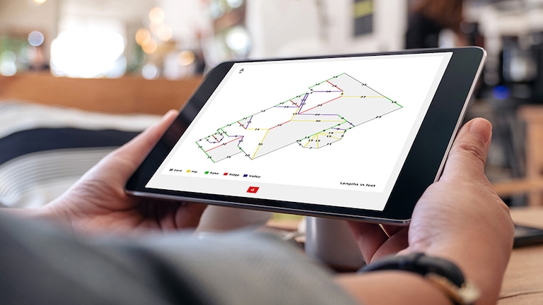 Hands holding tablet with GAF QuickMeasure roof measurements