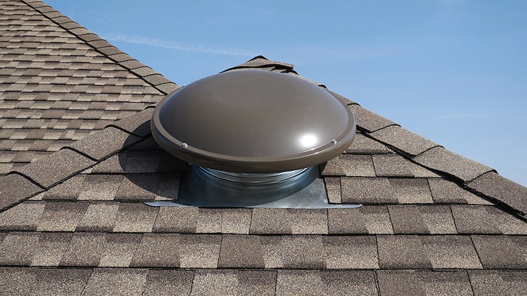 Sideview of a  GAF brand wind turbine that matches the brown asphalt shingles on a sloped roof