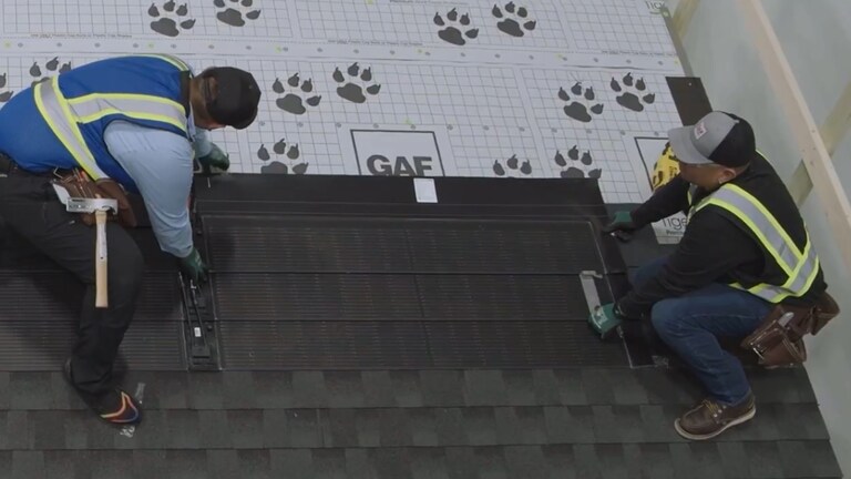 Roofers demonstrating solar roofing installation as part of training offered by GAF. 