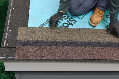 Roofer positioning and cutting StarterMatch starter strip shingles over roof underlayment.