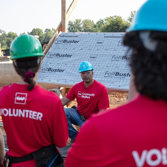 Roofing Academy trainer Gary Pierson speaking to volunteers at a construction site. 