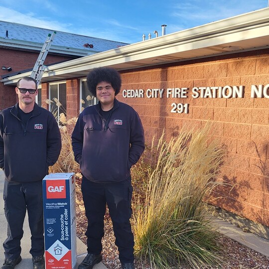 Cedar City Firefighters posing with GAF roofing products in front of a fire station