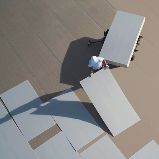 Overhead view of a GAF certified contractor laying down large polyiso insulation boards on a commercial roof.