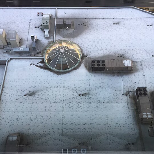 Aerial view of a commercial roof revealing dark spots around fasteners due to thermal bridging.