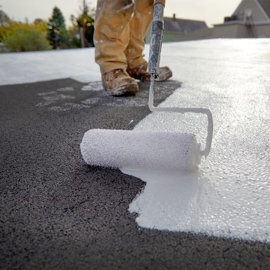 A roofer applies a silicone roof coating