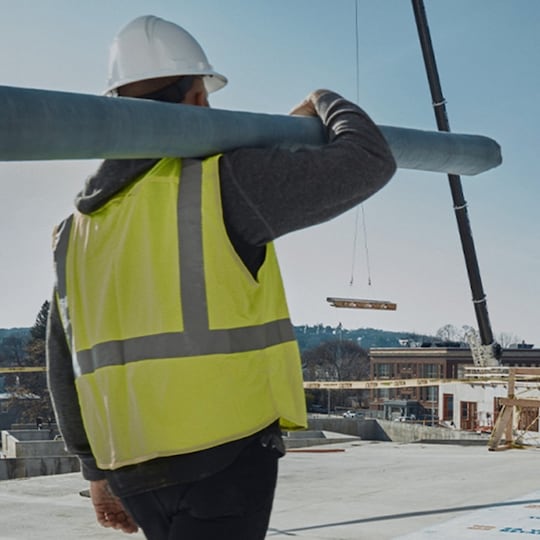 Contractor holding roofing materials walking on the roof of the Revington