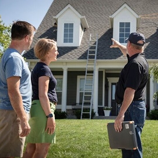 A contractor discussing roofing warranties with a homeowner couple. 