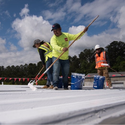Contratistas de GAF aplican revestimientos sobre un techo plano.