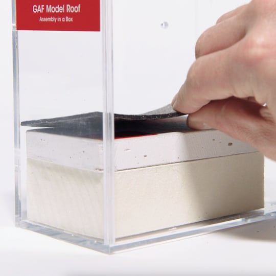 A close-up of a GAF certified commercial contractor assembling a potential commercial roof using the Model Roof layers.