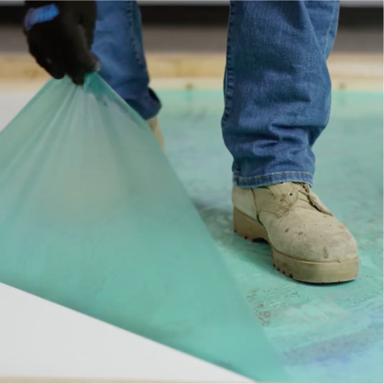Un contratista Certified™ de GAF despega la película protectora EverGuard MembraneShield de una membrana para techos blanca.