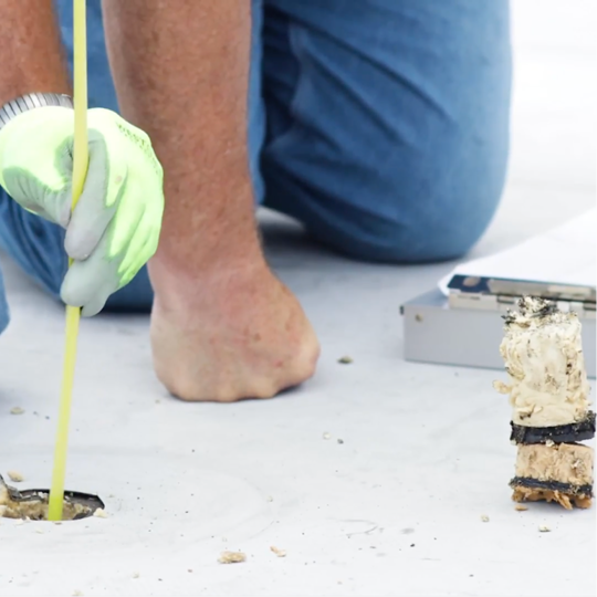 A GAF certified contractor probing a roof penetration during a commercial reroofing project inspection.