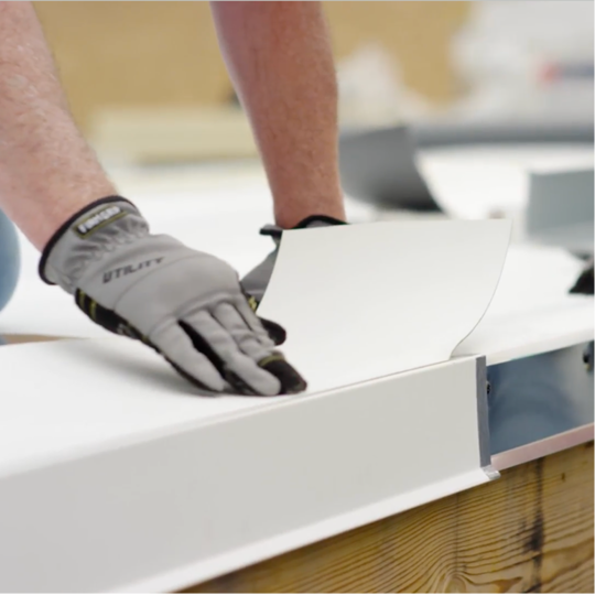 A GAF certified contractor positioning a white TPO roof edge detail.