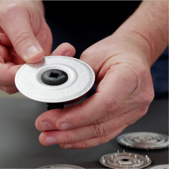 Close-up shot of a GAF certified contractor holding a GAF stress plate and fastener assembly.