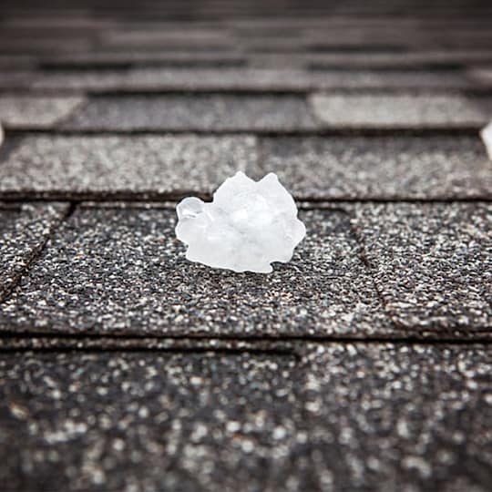 An asphalt shingle roof with hail balls laying on it.