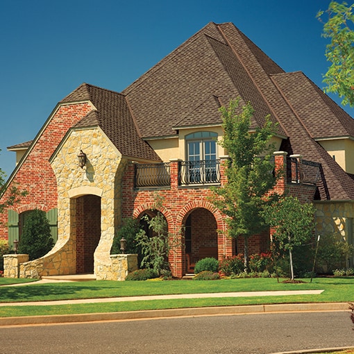 A brick home with brown Grand Sequoia® AS roof shingles that meet the criteria of the FORTIFIED™ Program.