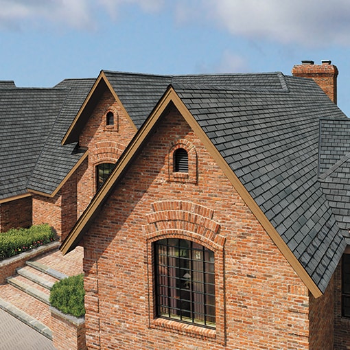 A red brick house with gray Slateline® shingles by GAF that meet the criteria of the FORTIFIED™ Program.