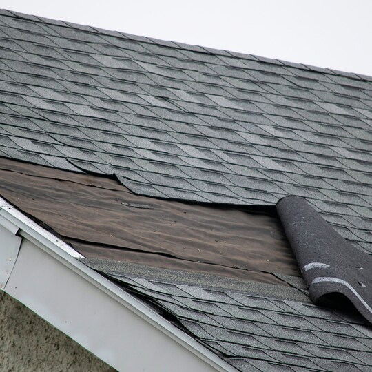 Wind damage to roof on home with gray shingles.