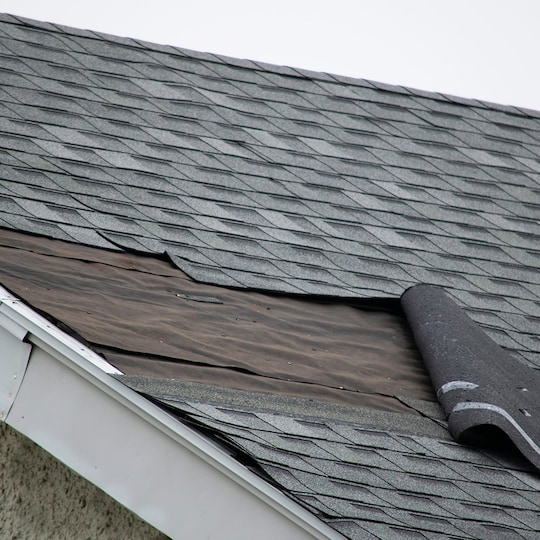 Wind damage to roof on home with gray shingles.