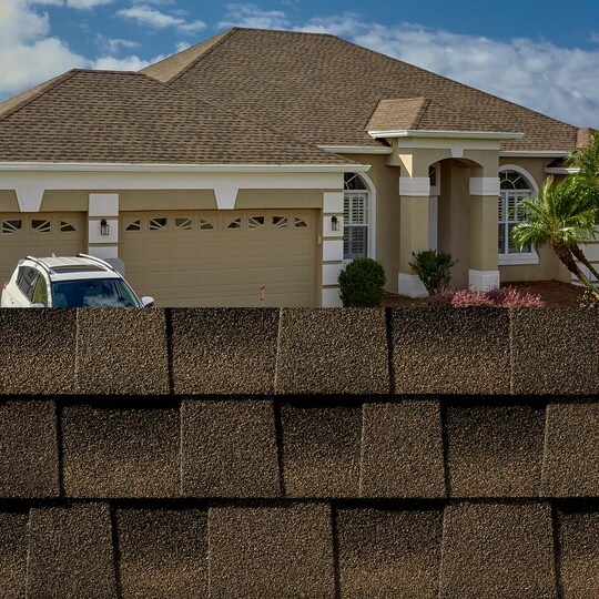 GAF Timberline HDZ® Barkwood Shingle closeup with sample product image on a taupe house.