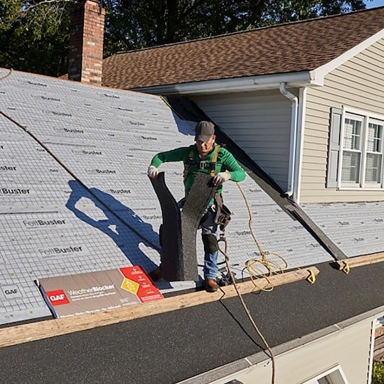 A roofer separating a shingle starter strip before installing a new GAF roof.