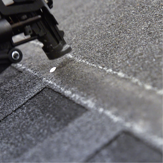 Close-up of a roofer’s nail gun securing shingles to a roofz