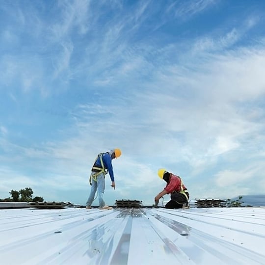 Two GAF certified commercial roofing contractors working on a commercial flat roof.