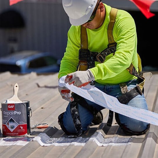 Close-up of a GAF certified commercial roofing contractor using a GAF RepairPro product on a flat roof.