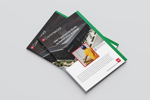 The "GAF Commercial Guide to Sustainable Building" brochure rests on a white surface, featuring a cover photo of a modern building and a GAF Commercial Certified contractor at work.