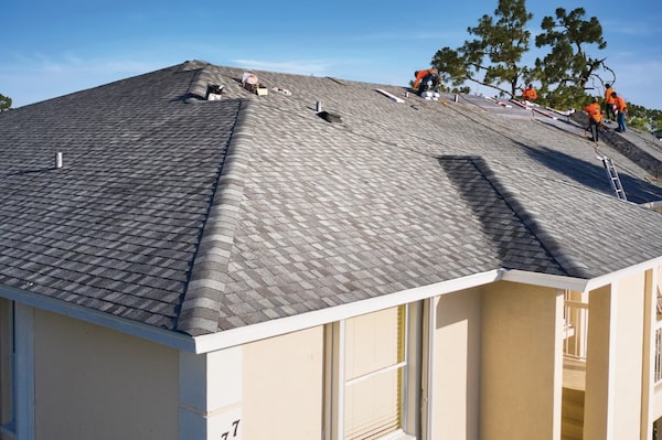 Roofing team installing new gray roof on stucco home