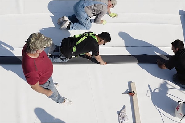  A crew of GAF certified commercial contractors installing commercial flat roof materials.