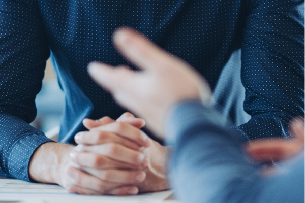 A close-up, blurred view of two people engaged in a professional discussion at a table.