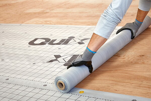 A roofer unrolling Quix product on a board