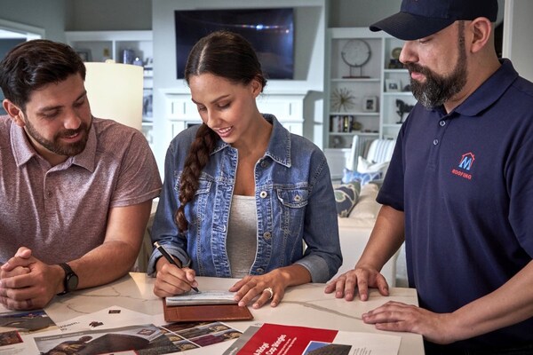Man and woman homeowners working on roofing financing options with their GAF certified contractor