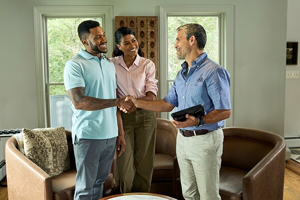 A roofing company’s representative talking to homeowners in their living room about an upcoming project.