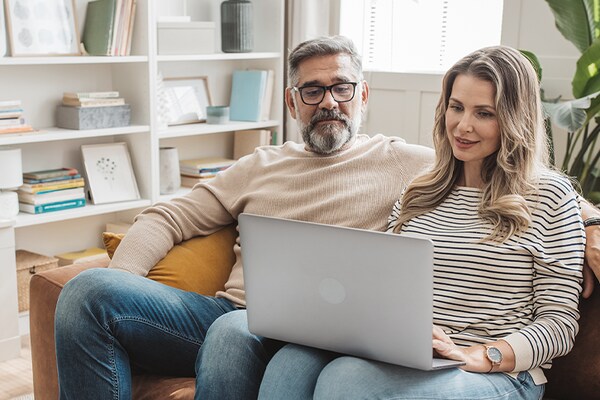 A seated homeowner couple browses GAF’s  website for roofing contractors on a laptop.